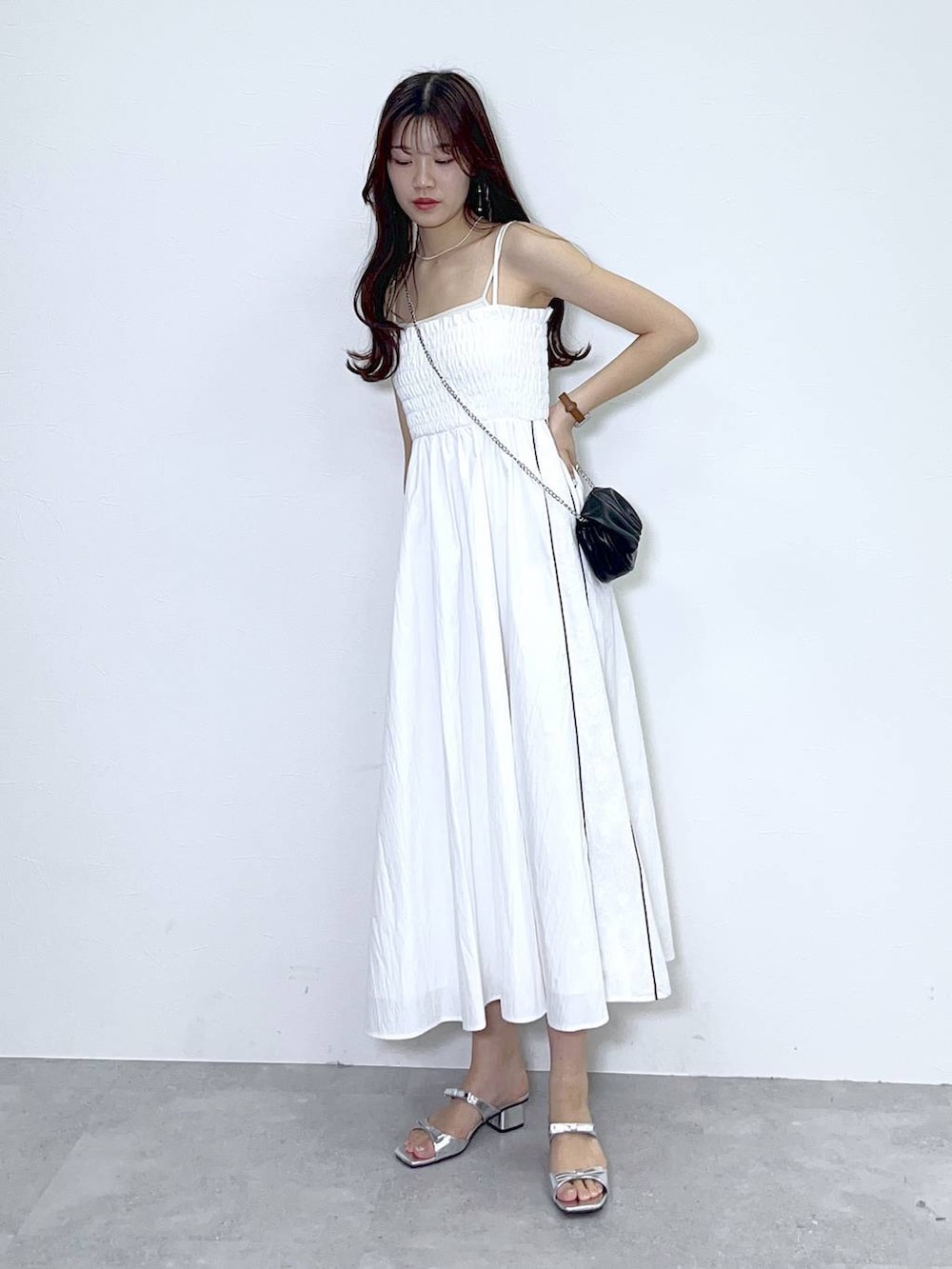 ブラック系のショルダーバッグ、シルバー系のサンダル、ホワイト系のワンピースを着用したレディースの夏コーディネートの6枚目の写真