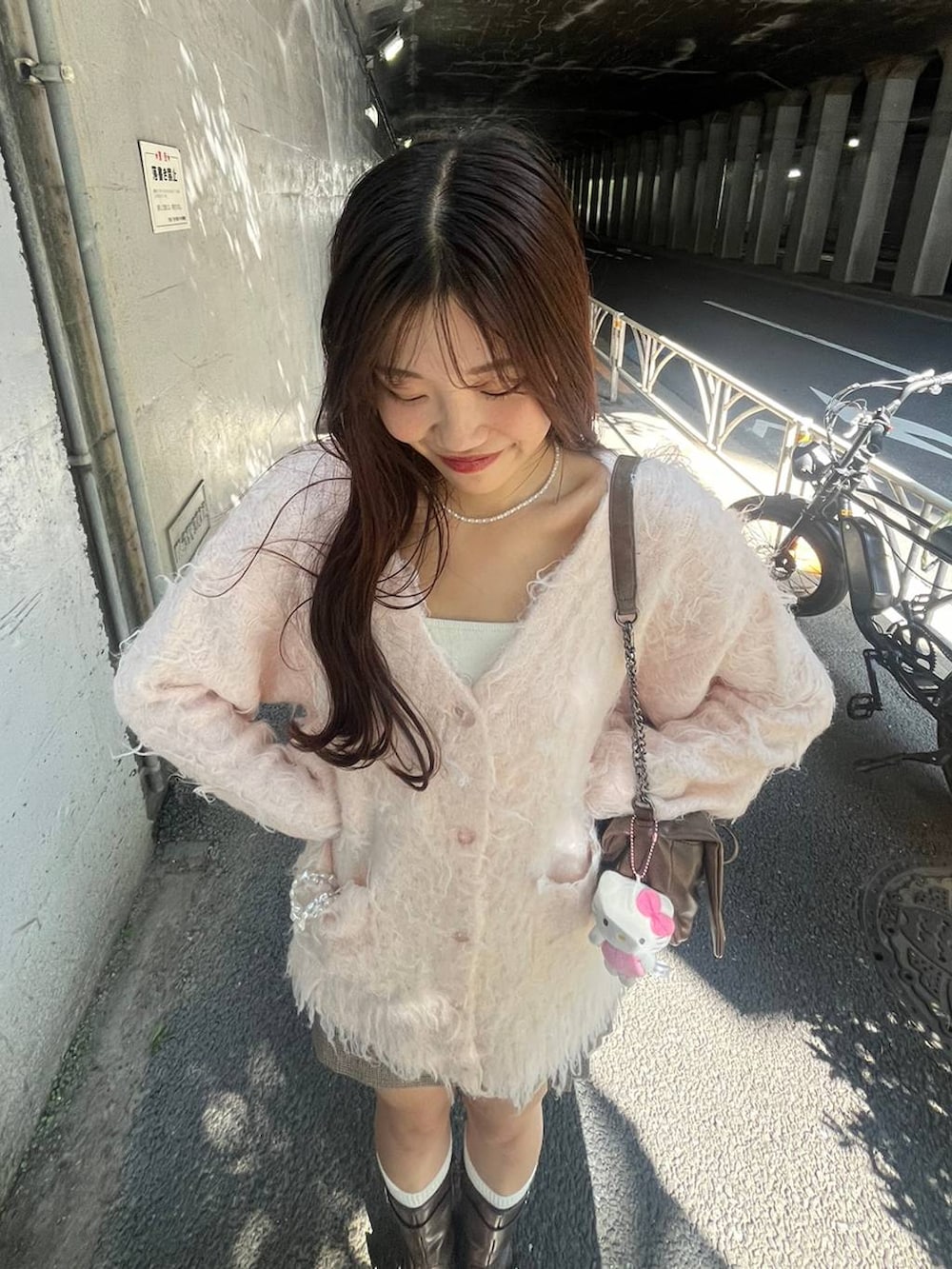 ブラウン系のショルダーバッグ、ブラウン系のブーツ、ホワイト系のキャミソールを着用したレディースの秋コーディネートの3枚目の写真