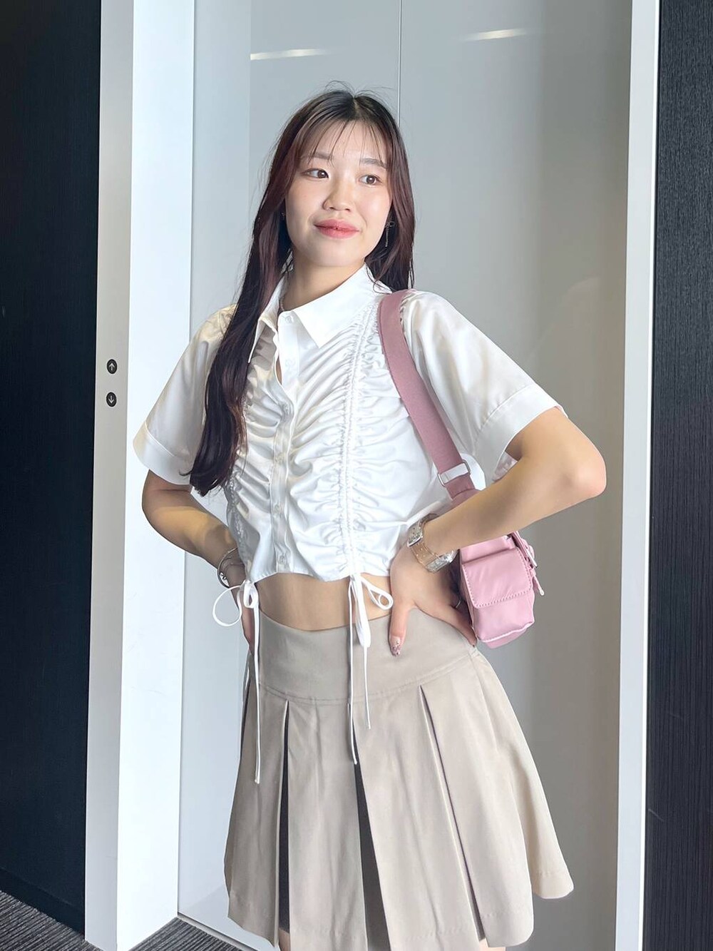 ピンク系のショルダーバッグ、ホワイト系のキャミソール、ベージュ系のスカートを着用したレディースの夏コーディネートの2枚目の写真