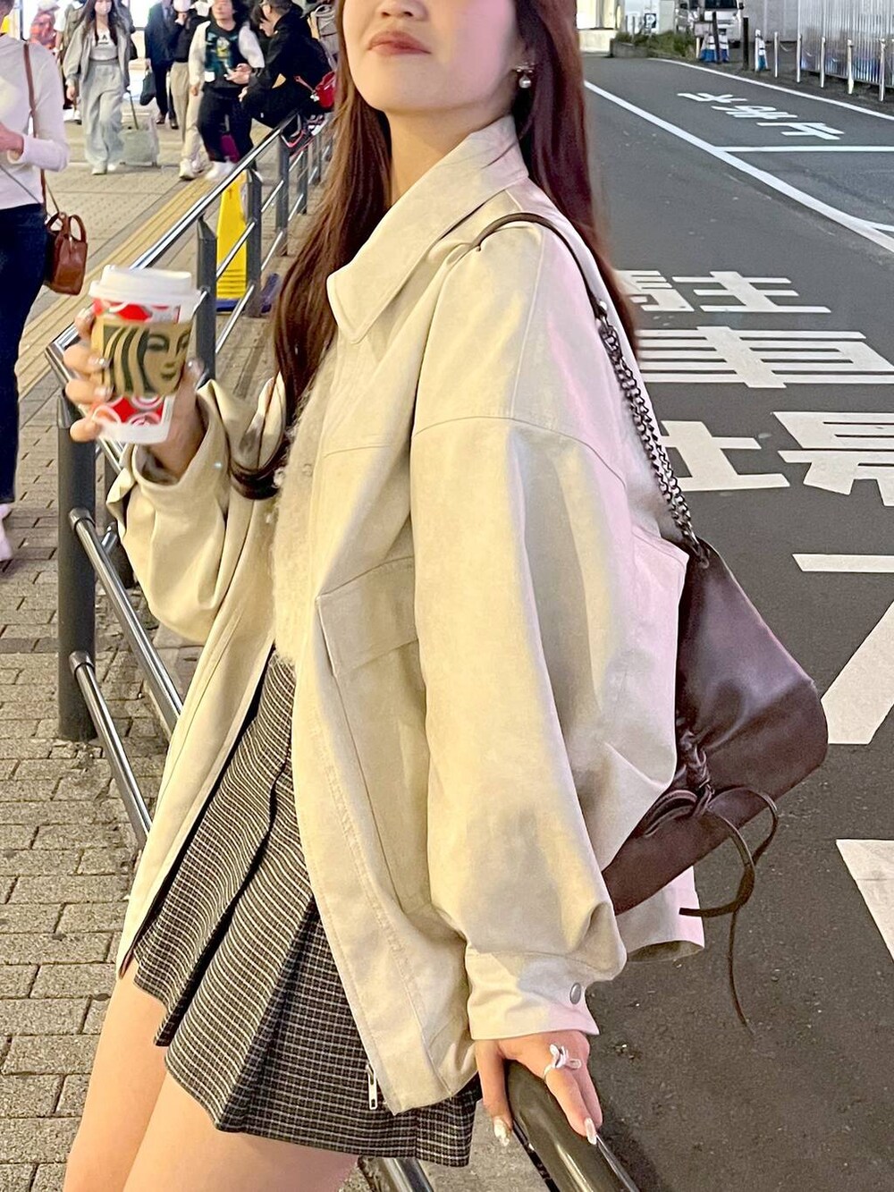 ブラウン系のショルダーバッグ、ベージュ系のスカート、ブラック系のブーツを着用したレディースの秋コーディネートの6枚目の写真