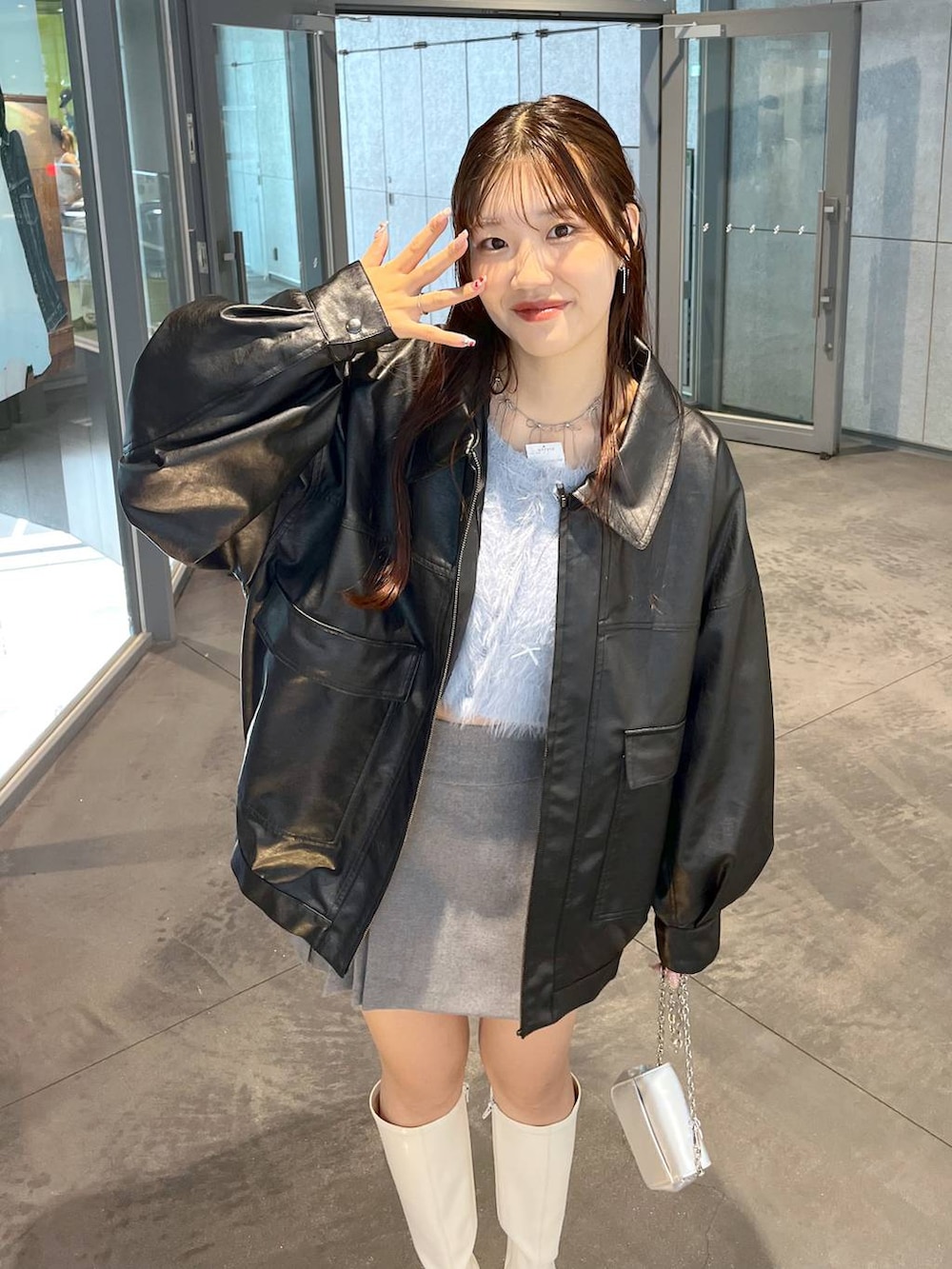 グレー系のスカート、ホワイト系のブーツ、ブラック系のブルゾンを着用したレディースの秋コーディネートの6枚目の写真