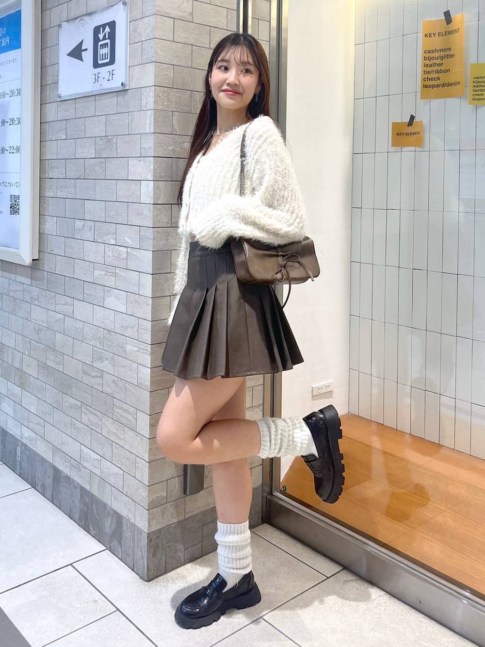 ブラウン系のショルダーバッグ、ホワイト系のアンサンブル、ホワイト系のキャミソールを着用したレディースの秋コーディネートの7枚目の写真