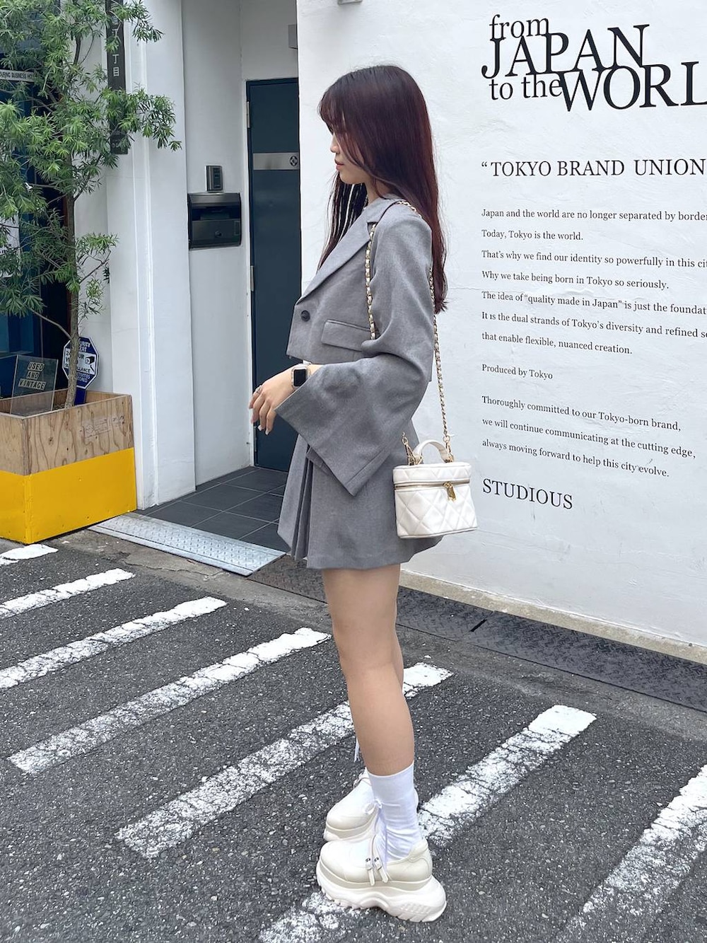 グレー系のテーラードジャケット、ホワイト系のショルダーバッグ、ホワイト系のキャミソールを着用したレディースの夏コーディネートの4枚目の写真