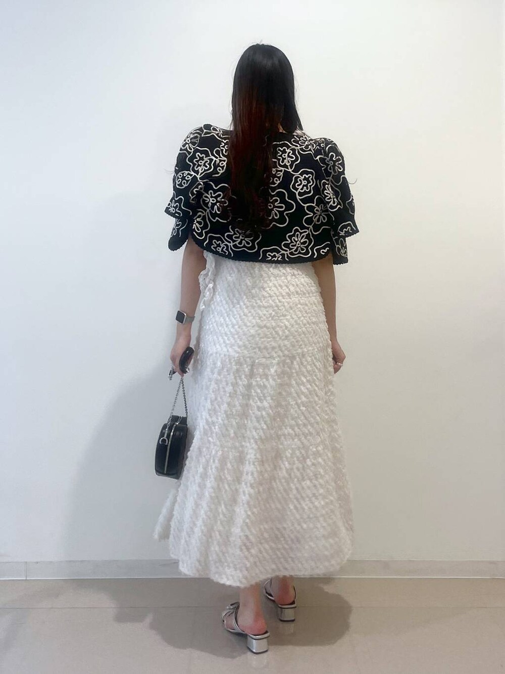 シルバー系のサンダル、ホワイト系のワンピース、ブラック系のショルダーバッグを着用したレディースの春コーディネートの3枚目の写真