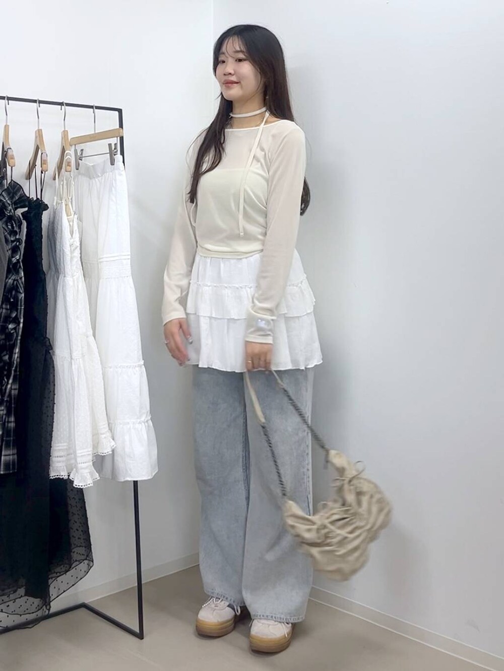 ホワイト系のキャミソール、ブルー系のデニムパンツ、ホワイト系のスカートを着用したレディースの春コーディネートの6枚目の写真