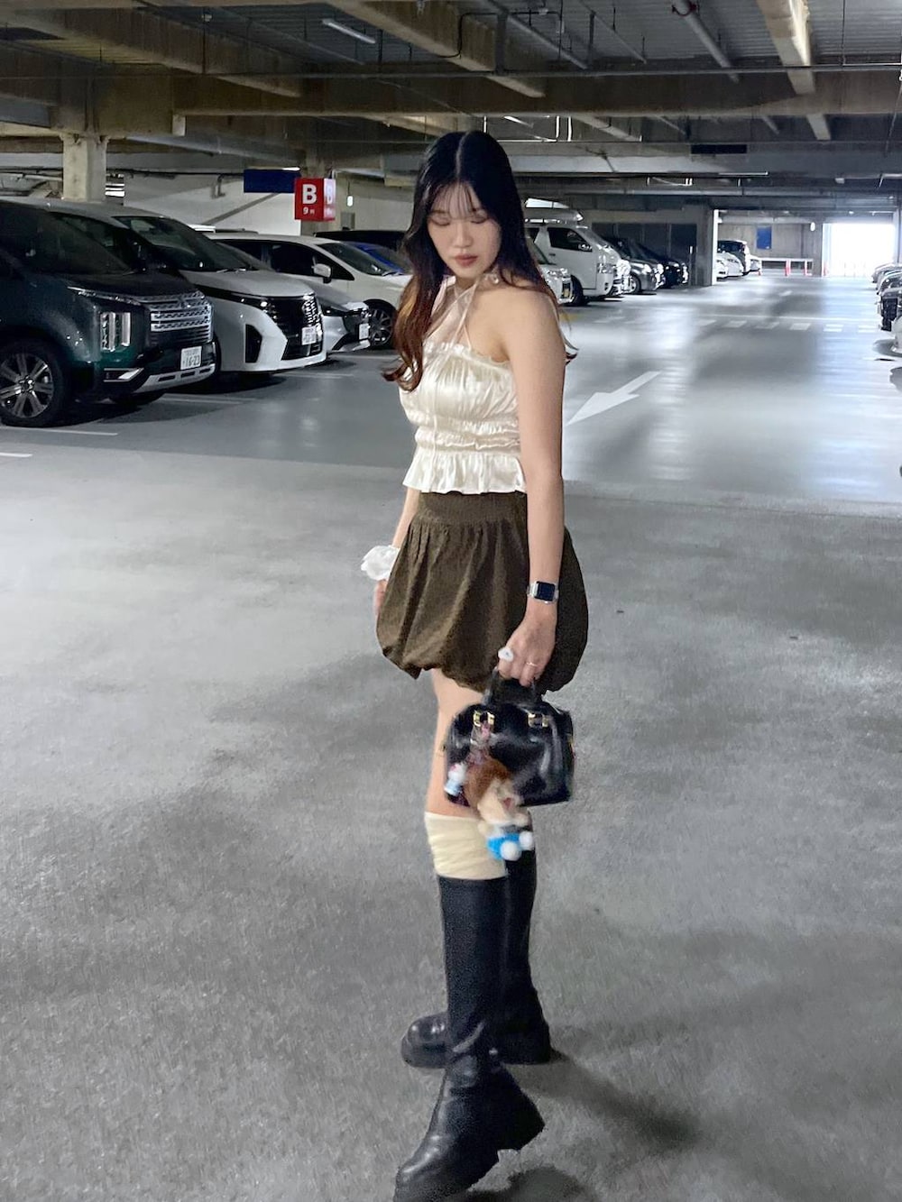 ブラック系のブーツ、ホワイト系のキャミソール、ブラウン系のスカートを着用したレディースの夏コーディネートの5枚目の写真