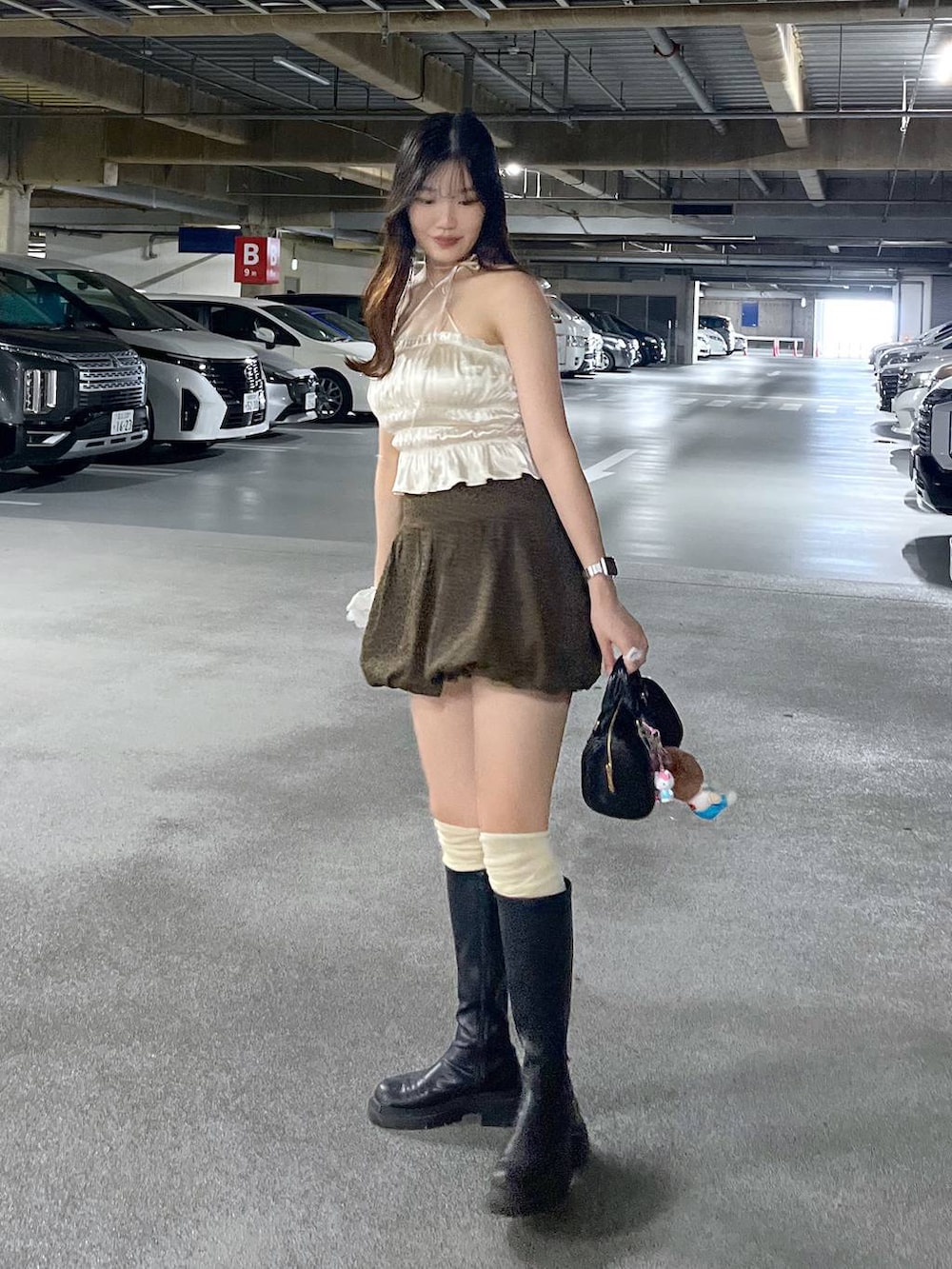 ブラック系のブーツ、ホワイト系のキャミソール、ブラウン系のスカートを着用したレディースの夏コーディネートの2枚目の写真