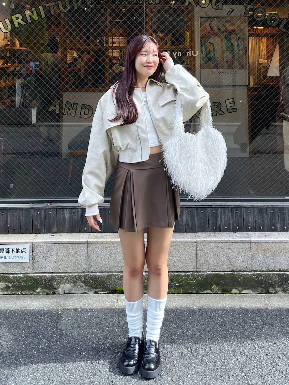 ブラウン系のスカート、ホワイト系のショルダーバッグ、ブラック系のローファーを着用したレディースの秋コーディネートの3枚目の写真