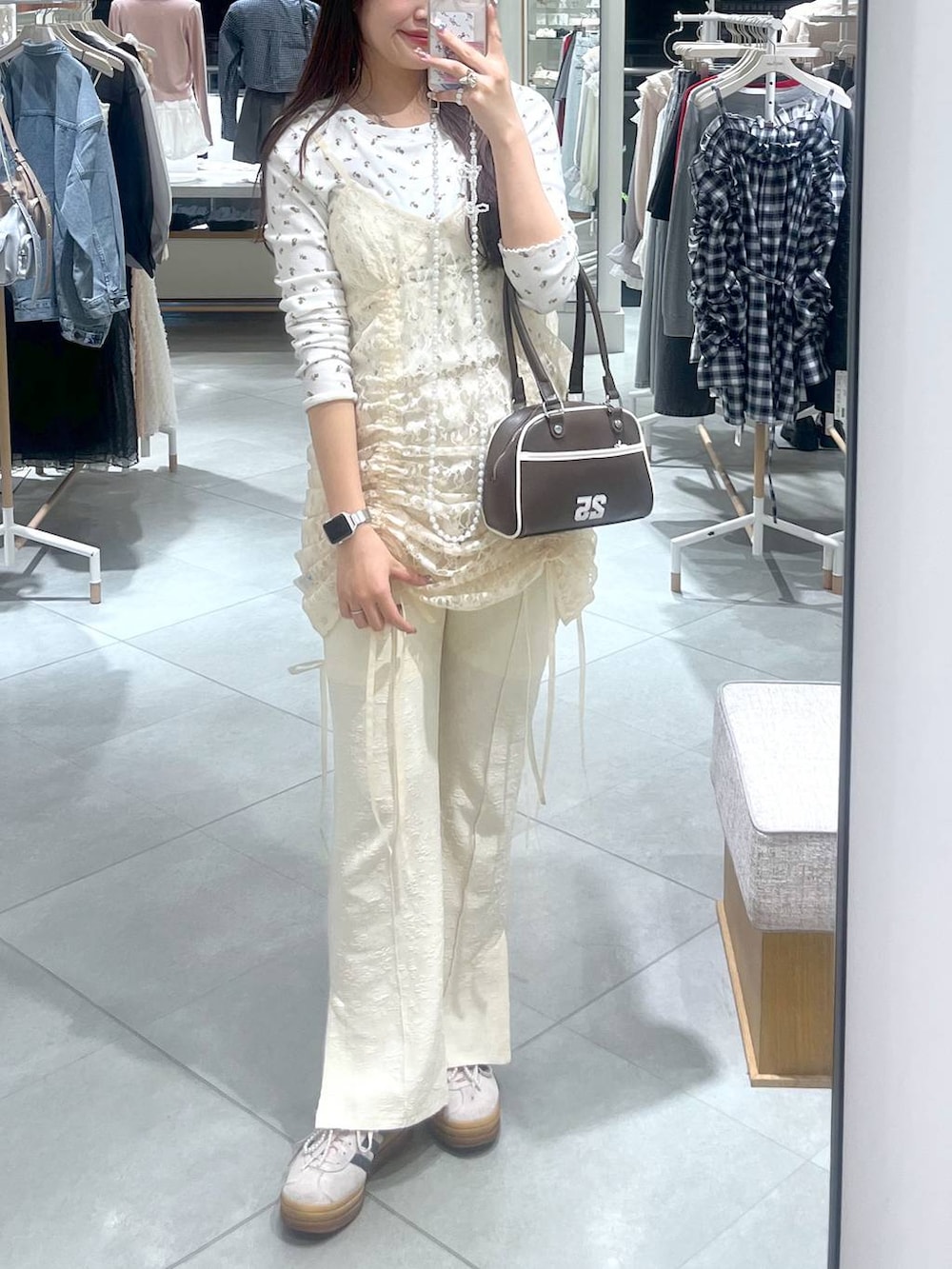 ベージュ系のワンピース、ブラウン系のボストンバッグ、ホワイト系のスマホグッズを着用したレディースの春コーディネートの3枚目の写真