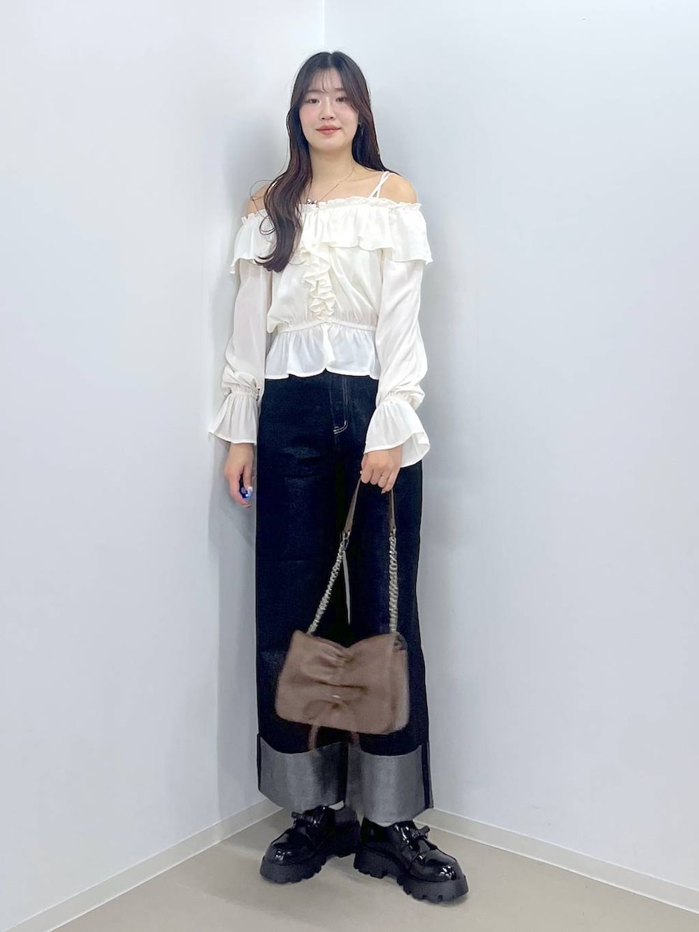 ブラウン系のショルダーバッグ、ホワイト系のキャミソール、ブラック系のドレスシューズを着用したレディースの冬コーディネートの5枚目の写真