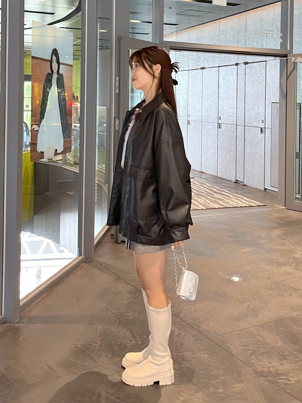 グレー系のスカート、ホワイト系のブーツ、ブラック系のブルゾンを着用したレディースの秋コーディネートの7枚目の写真