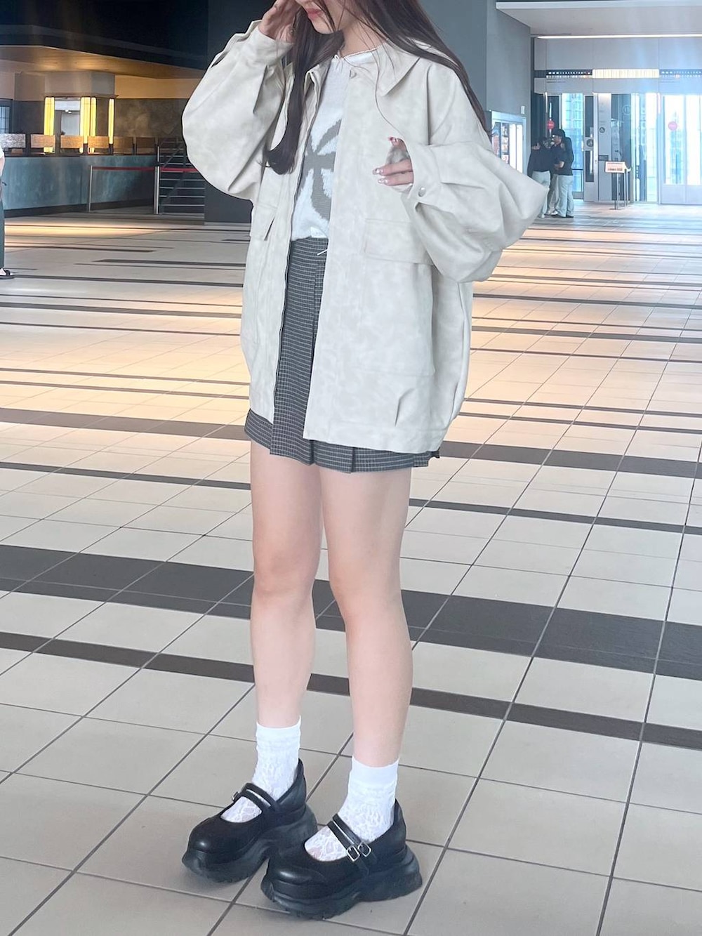 ブラック系のスニーカー、ホワイト系のキャミソール、ホワイト系のブルゾンを着用したレディースの秋コーディネートの4枚目の写真