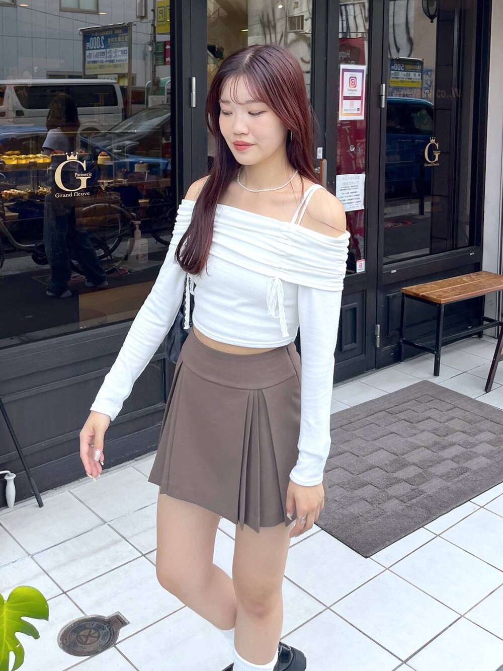 ブラウン系のスカート、グレー系のショルダーバッグ、ホワイト系のキャミソールを着用したレディースの秋コーディネートの2枚目の写真