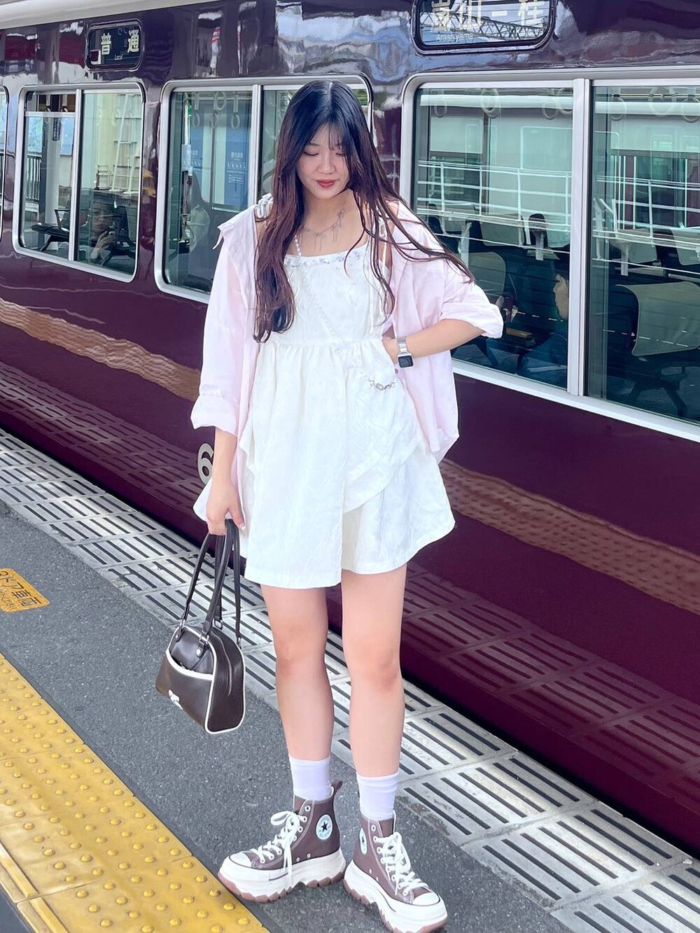 ホワイト系のワンピース、ホワイト系のカーディガン/ボレロ、ブラウン系のボストンバッグを着用したレディースの春コーディネートの3枚目の写真