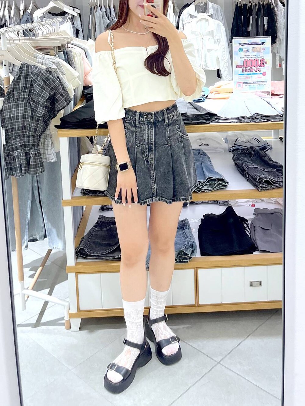 ブラック系のデニムスカート、ブラック系のサンダル、ホワイト系のショルダーバッグを着用したレディースの夏コーディネートの5枚目の写真