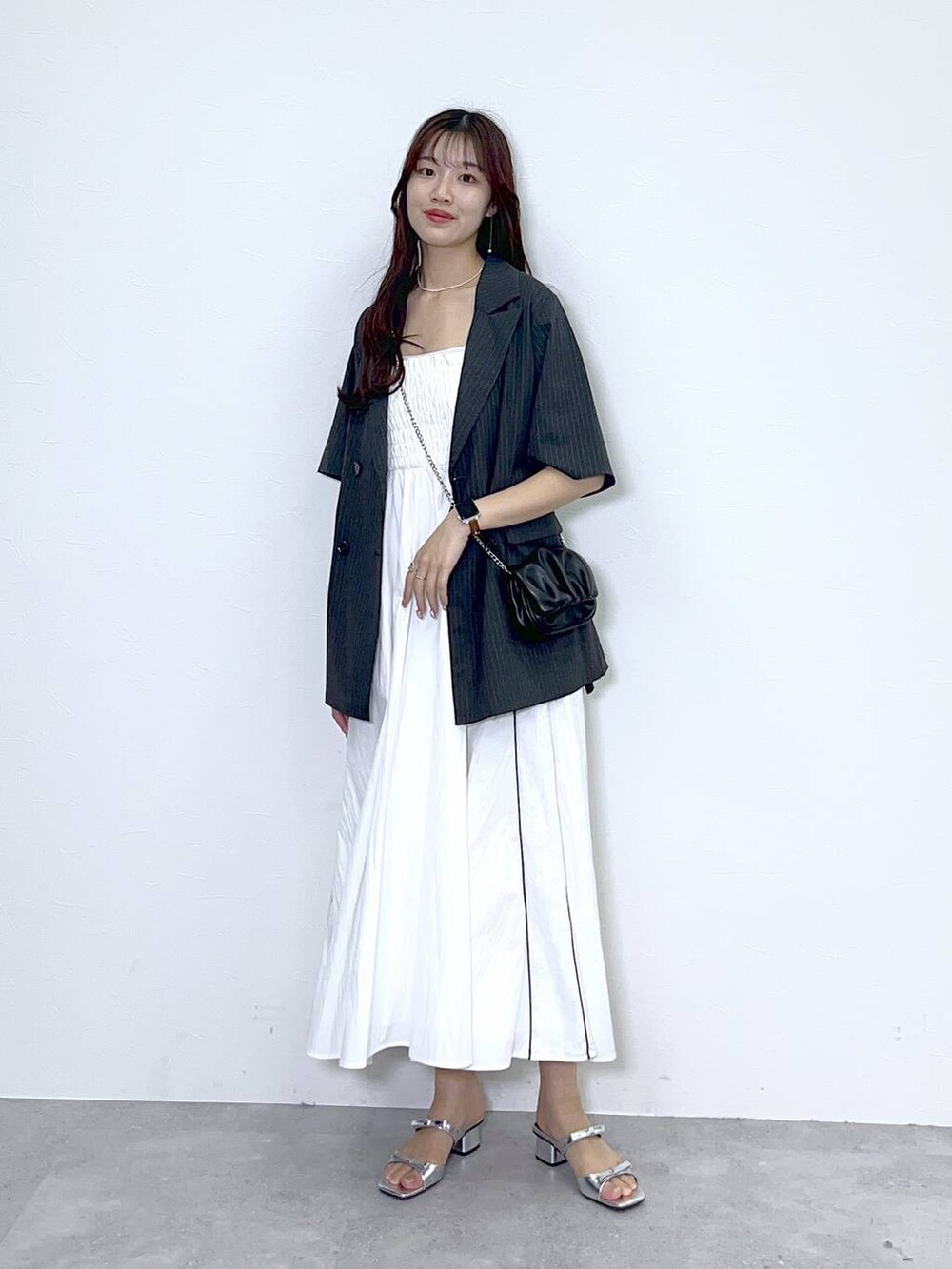 ブラック系のショルダーバッグ、シルバー系のサンダル、ホワイト系のワンピースを着用したレディースの夏コーディネートの2枚目の写真