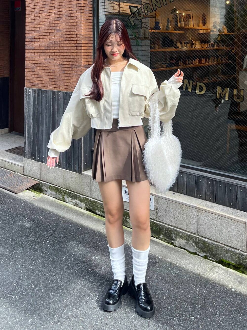 ブラウン系のスカート、ホワイト系のショルダーバッグ、ブラック系のローファーを着用したレディースの秋コーディネートの7枚目の写真