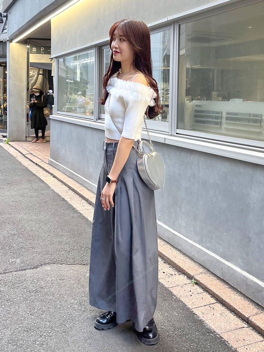 シルバー系のショルダーバッグ、グレー系のスラックス、ホワイト系のキャミソールを着用したレディースの夏コーディネートの2枚目の写真