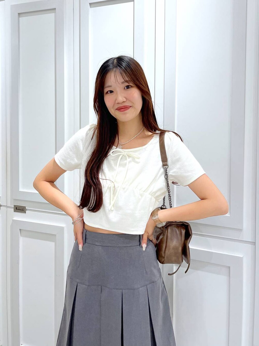 ブラウン系のショルダーバッグ、グレー系のスカート、ホワイト系のキャミソールを着用したレディースの夏コーディネートの2枚目の写真