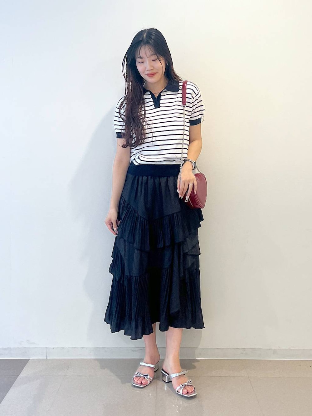 ホワイト系のキャミソール、ブラック系のスカート、シルバー系のサンダルを着用したレディースの春コーディネートの2枚目の写真