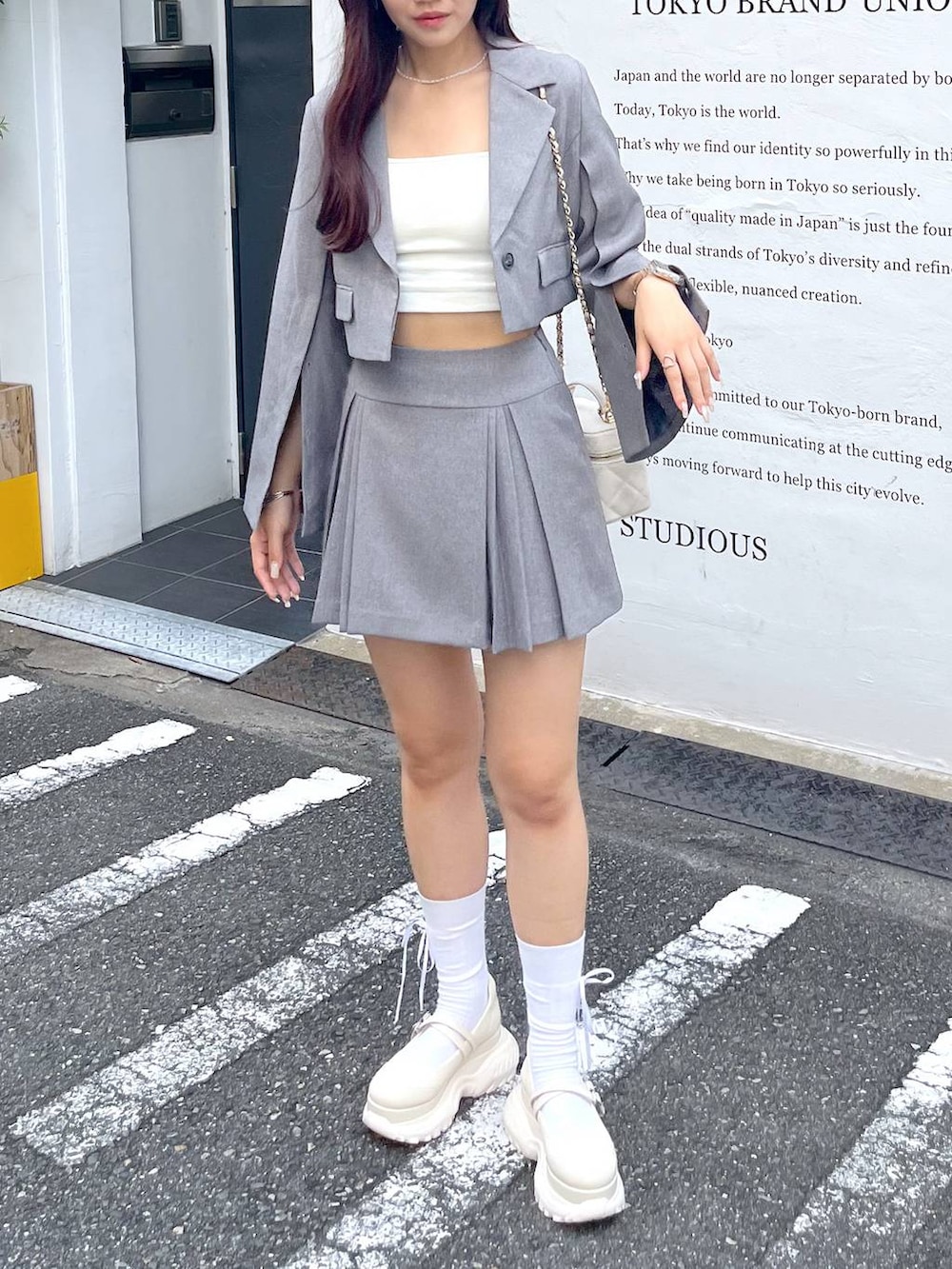 グレー系のテーラードジャケット、ホワイト系のショルダーバッグ、ホワイト系のキャミソールを着用したレディースの夏コーディネートの7枚目の写真