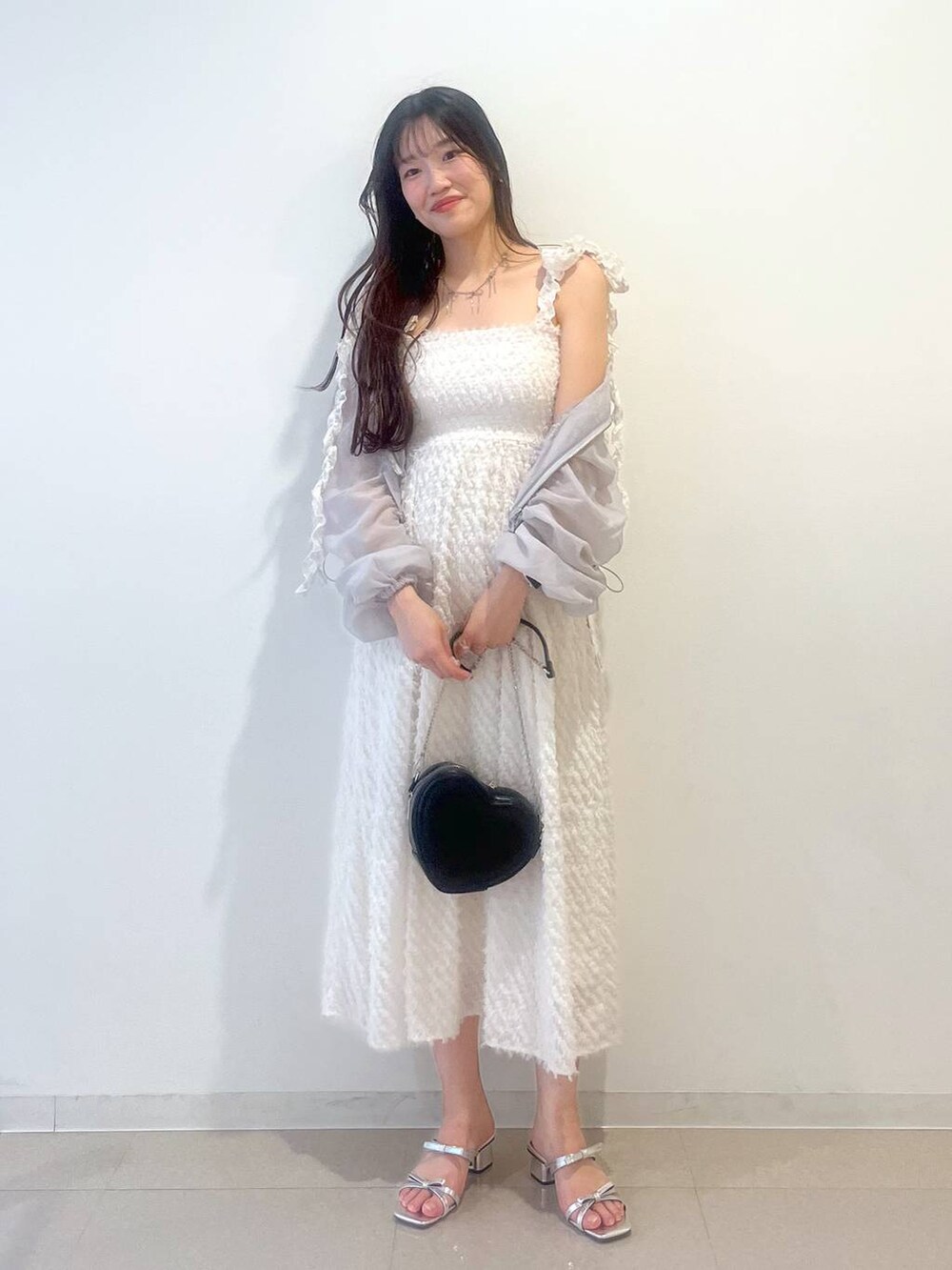 シルバー系のサンダル、ホワイト系のワンピース、グレー系のブルゾンを着用したレディースの春コーディネートの2枚目の写真