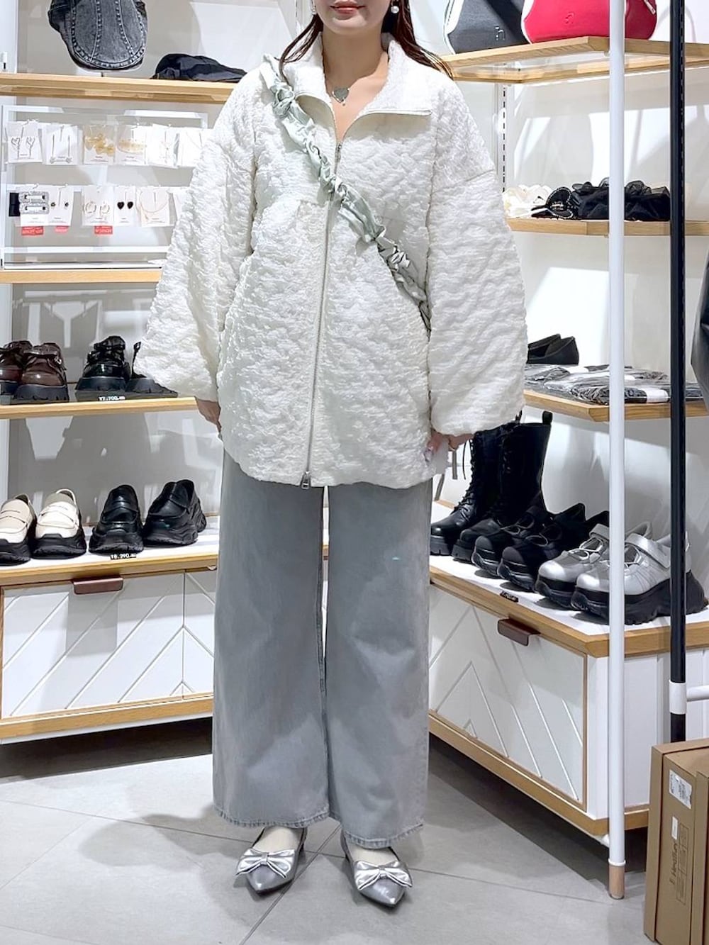 ブルー系のデニムパンツ、グリーン系のショルダーバッグ、シルバー系のパンプスを着用したレディースの春コーディネートの2枚目の写真