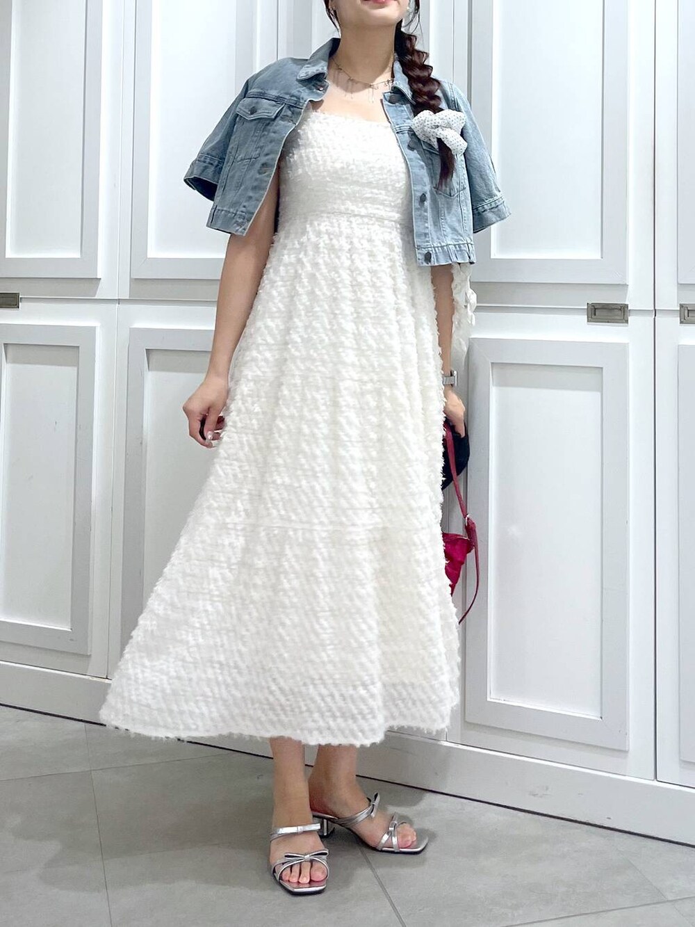 シルバー系のサンダル、ブルー系のデニムジャケット、ホワイト系のワンピースを着用したレディースの春コーディネートの2枚目の写真