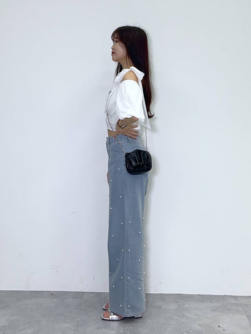 ブラック系のショルダーバッグ、ホワイト系のキャミソール、ブルー系のデニムパンツを着用したレディースの夏コーディネートの2枚目の写真