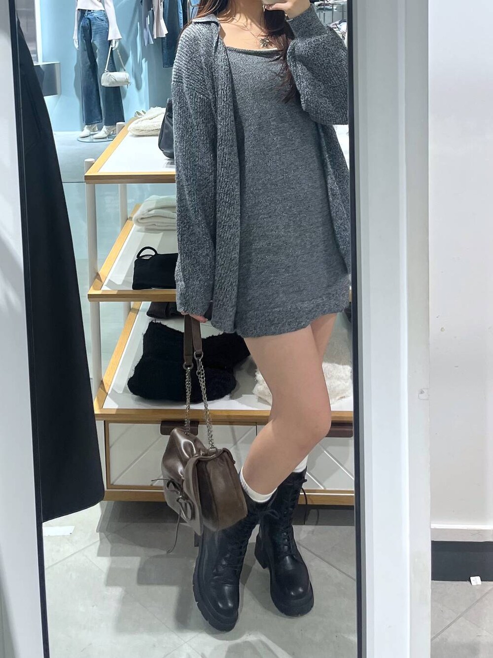 ブラウン系のショルダーバッグ、ブラック系のブーツ、ホワイト系のTシャツ/カットソーを着用したレディースの冬コーディネートの3枚目の写真