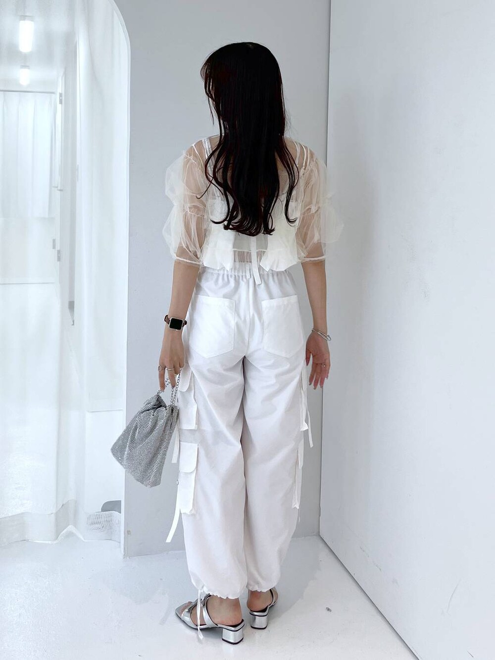 シルバー系のショルダーバッグ、ホワイト系のキャミソール、ホワイト系のベストを着用したレディースの夏コーディネートの3枚目の写真