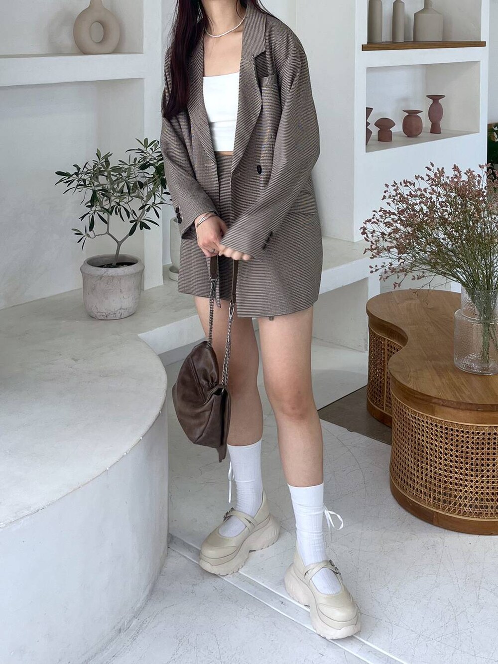 ブラウン系のショルダーバッグ、ホワイト系のキャミソール、ベージュ系のテーラードジャケットを着用したレディースの秋コーディネートの6枚目の写真