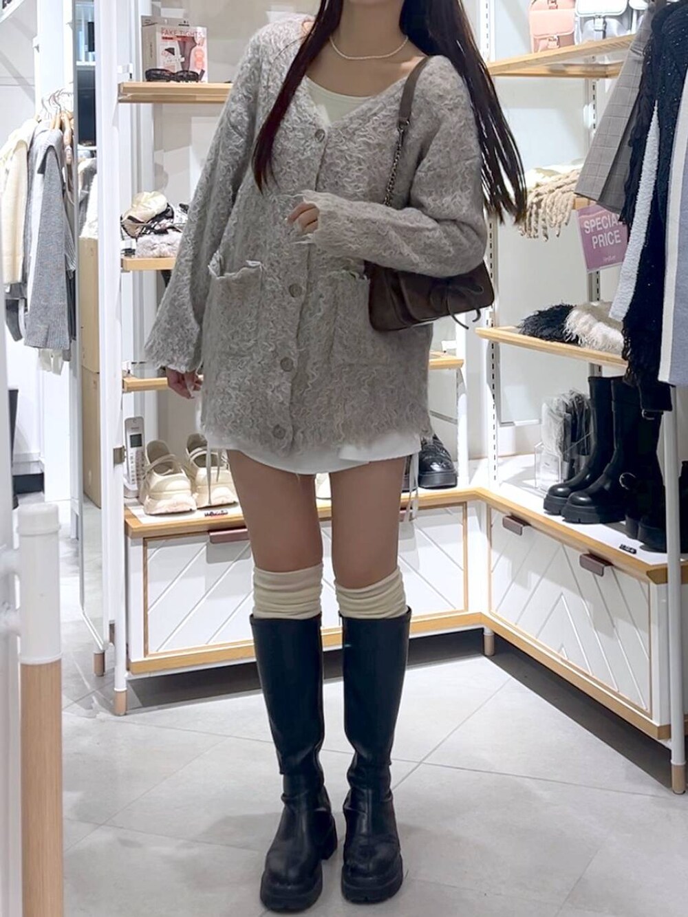 ブラウン系のショルダーバッグ、ホワイト系のTシャツ/カットソー、ブラック系のブーツを着用したレディースの冬コーディネートの3枚目の写真