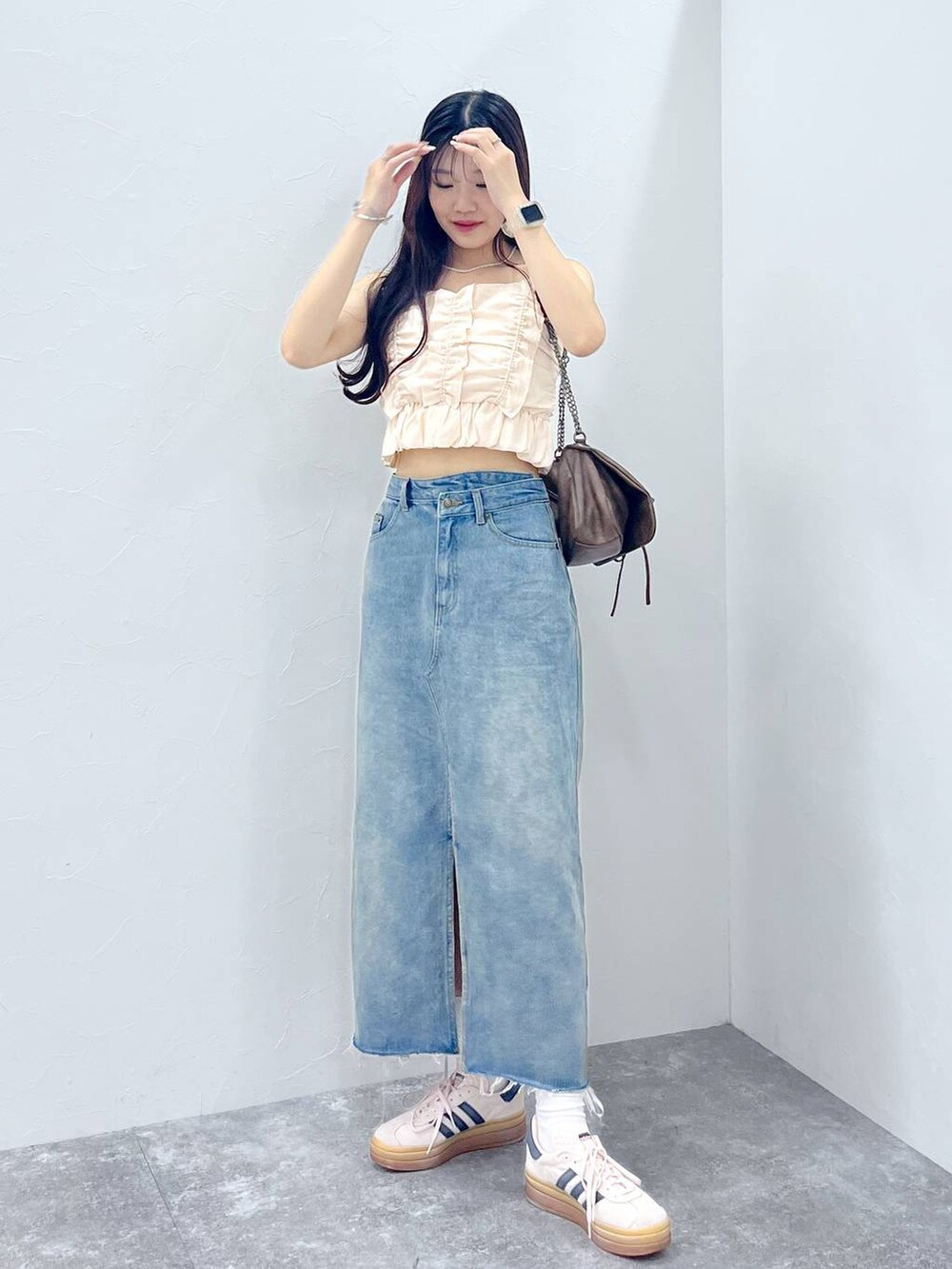 ブラウン系のショルダーバッグ、ホワイト系のキャミソール、ブルー系のデニムスカートを着用したレディースの夏コーディネートの4枚目の写真