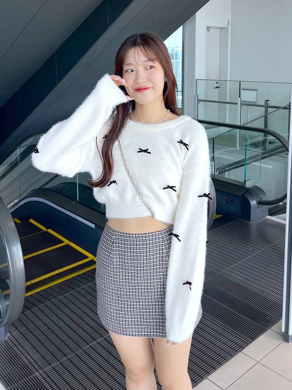 ブラック系のスカート、ホワイト系のニット/セーター、ブラック系のショルダーバッグを着用したレディースの秋コーディネートの7枚目の写真