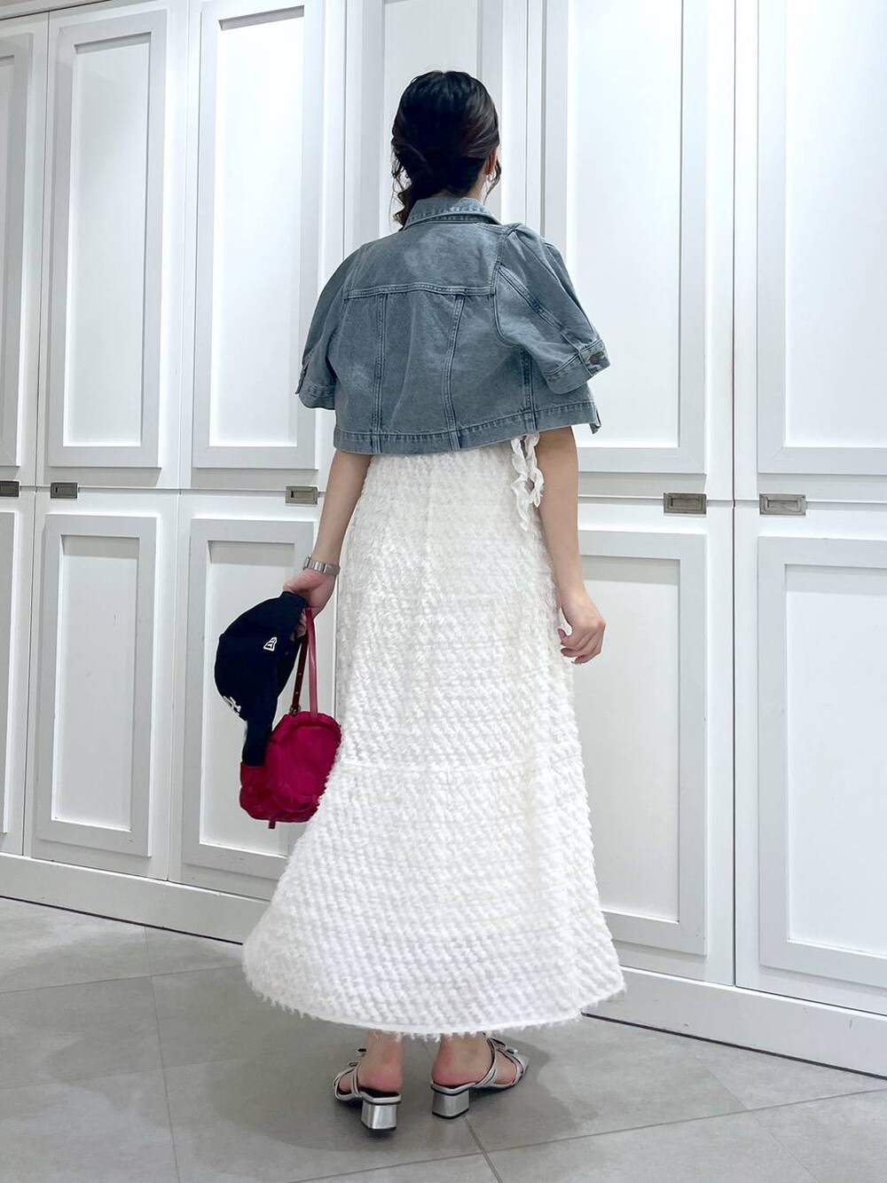 シルバー系のサンダル、ブルー系のデニムジャケット、ホワイト系のワンピースを着用したレディースの春コーディネートの5枚目の写真