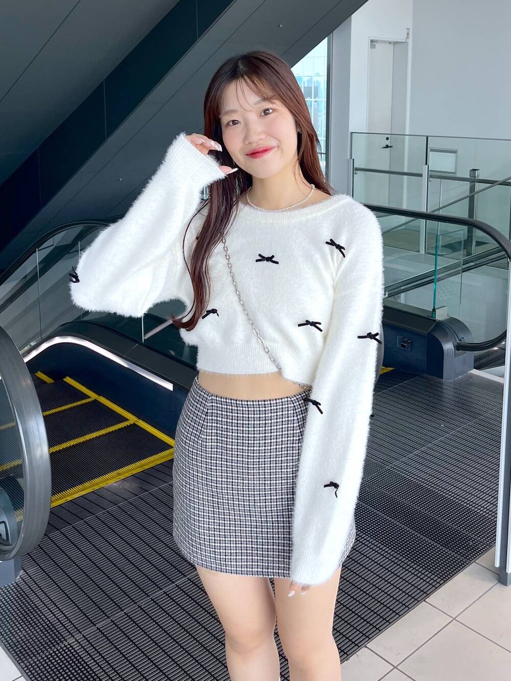 ブラック系のスカート、ホワイト系のニット/セーター、ブラック系のショルダーバッグを着用したレディースの秋コーディネートの5枚目の写真