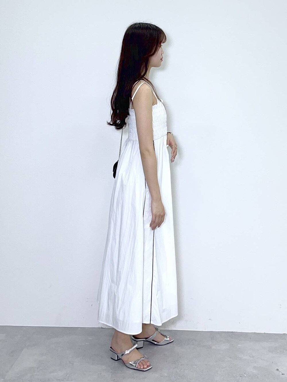 ブラック系のショルダーバッグ、シルバー系のサンダル、ホワイト系のワンピースを着用したレディースの夏コーディネートの2枚目の写真