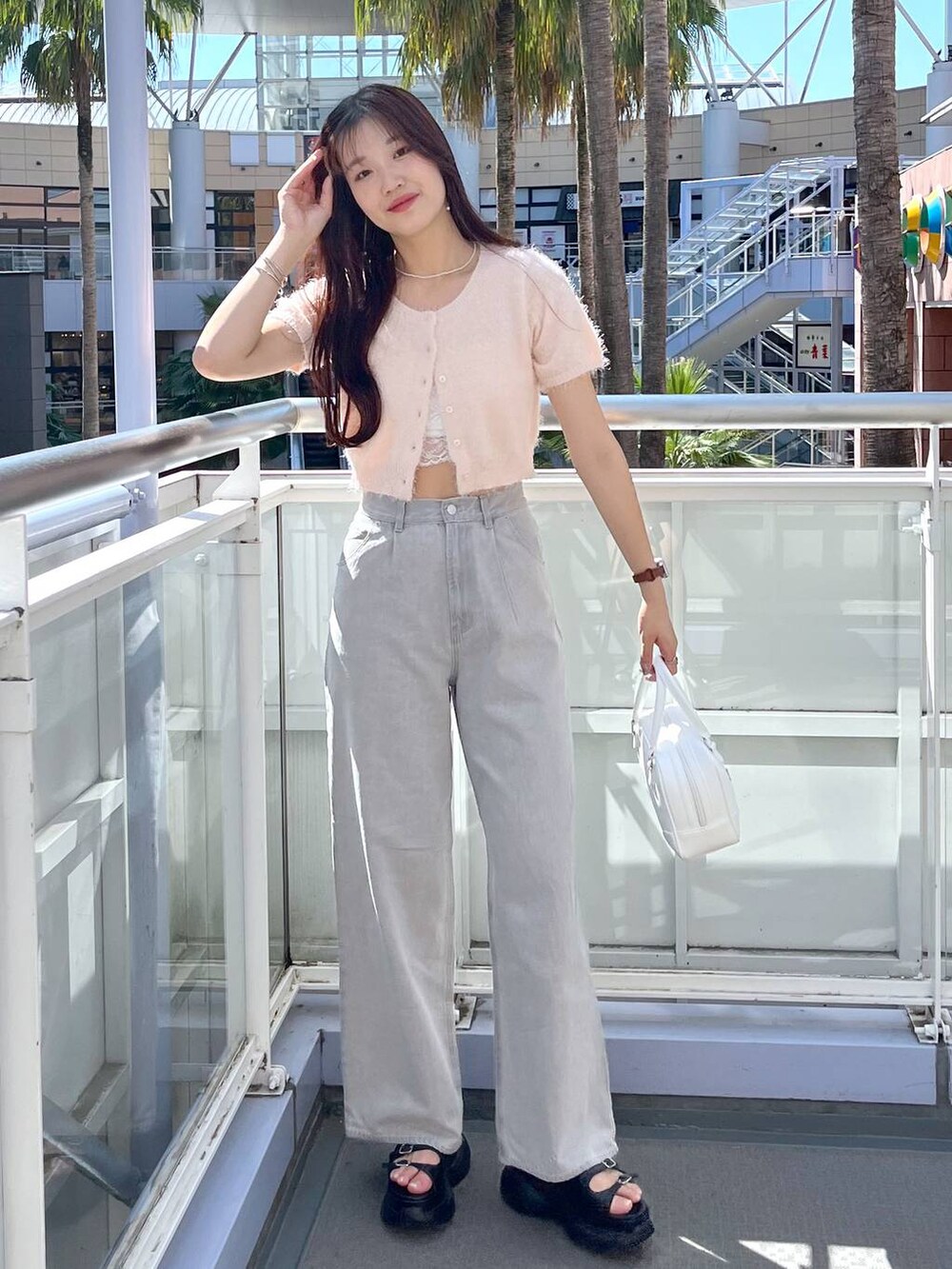 ピンク系のカーディガン/ボレロ、グレー系のデニムパンツ、ホワイト系のキャミソールを着用したレディースの夏コーディネートの2枚目の写真