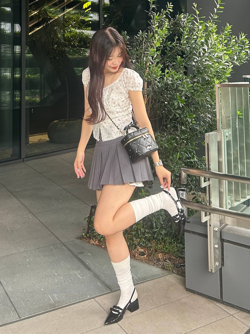 ブラック系のショルダーバッグ、グレー系のスカート、ブラック系のパンプスを着用したレディースの夏コーディネートの8枚目の写真