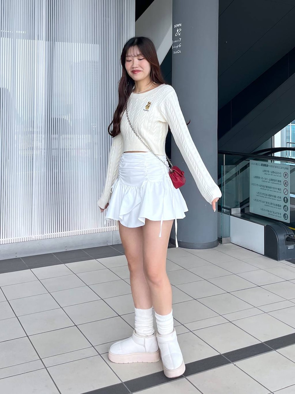 ホワイト系のTシャツ/カットソー、レッド系のショルダーバッグ、ホワイト系のブーツを着用したレディースの冬コーディネートの7枚目の写真