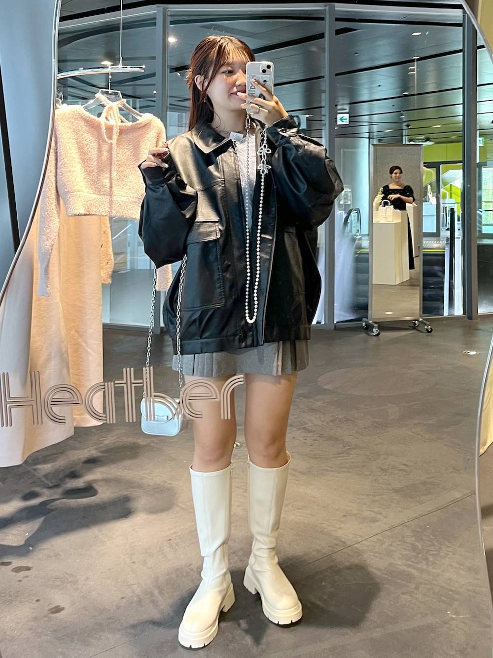 グレー系のスカート、ホワイト系のブーツ、ブラック系のブルゾンを着用したレディースの秋コーディネートの8枚目の写真