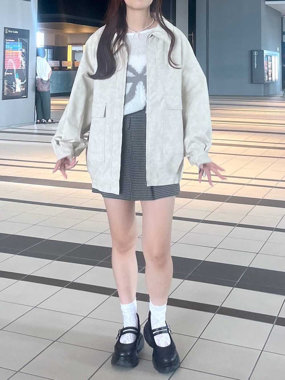 ブラック系のスニーカー、ホワイト系のキャミソール、ホワイト系のブルゾンを着用したレディースの秋コーディネートの7枚目の写真