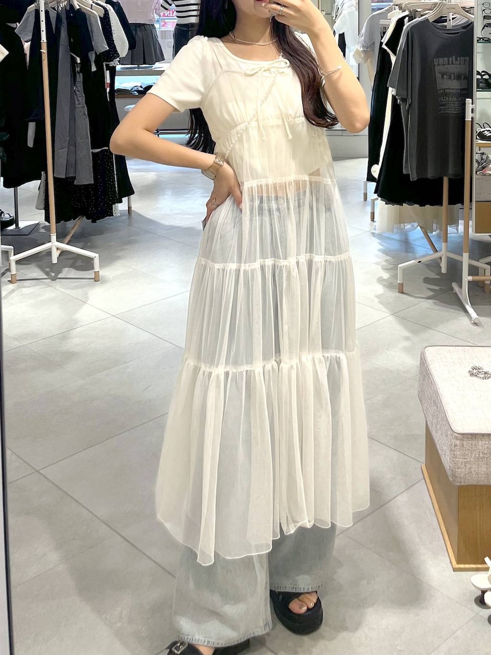 ホワイト系のワンピース、ホワイト系のキャミソール、ブルー系のデニムパンツを着用したレディースの夏コーディネートの7枚目の写真