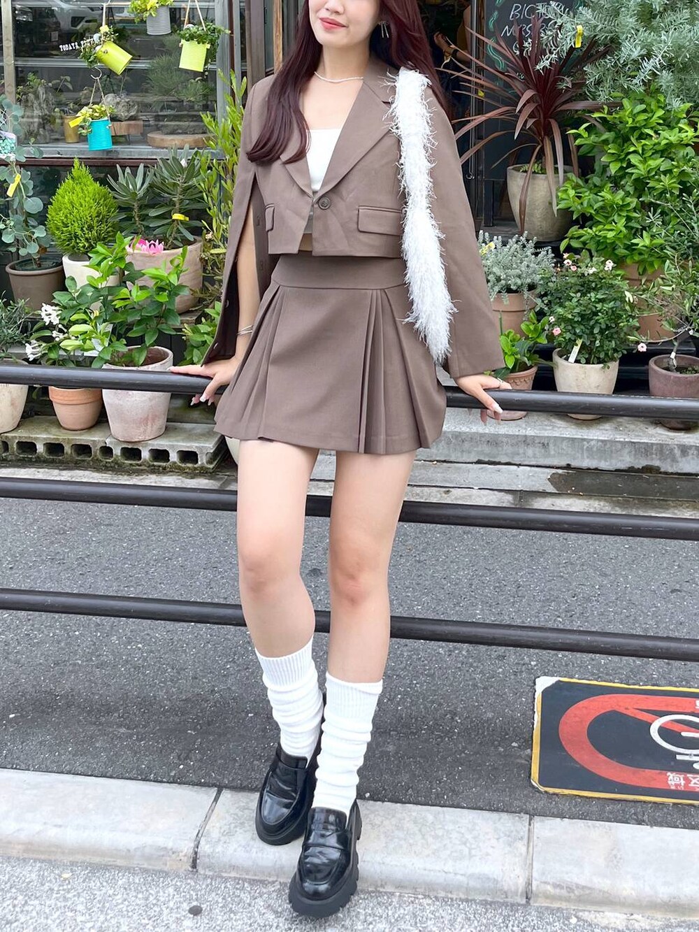 ブラウン系のテーラードジャケット、ブラウン系のスカート、ホワイト系のキャミソールを着用したレディースの夏コーディネートの3枚目の写真