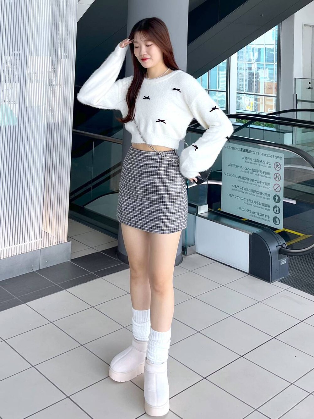 ブラック系のスカート、ホワイト系のニット/セーター、ブラック系のショルダーバッグを着用したレディースの秋コーディネートの2枚目の写真