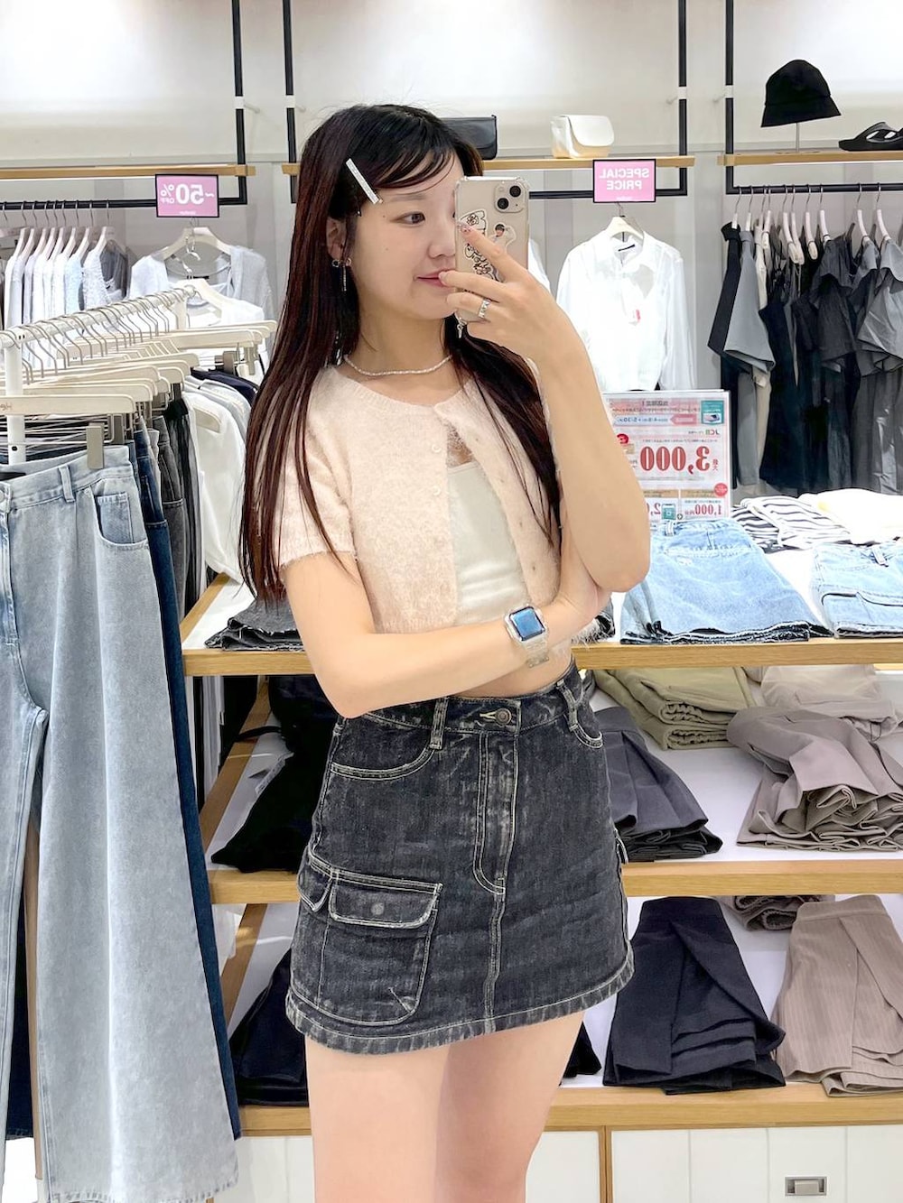 ピンク系のカーディガン/ボレロ、ホワイト系のキャミソール、ブラック系のデニムスカートを着用したレディースの春コーディネートの2枚目の写真