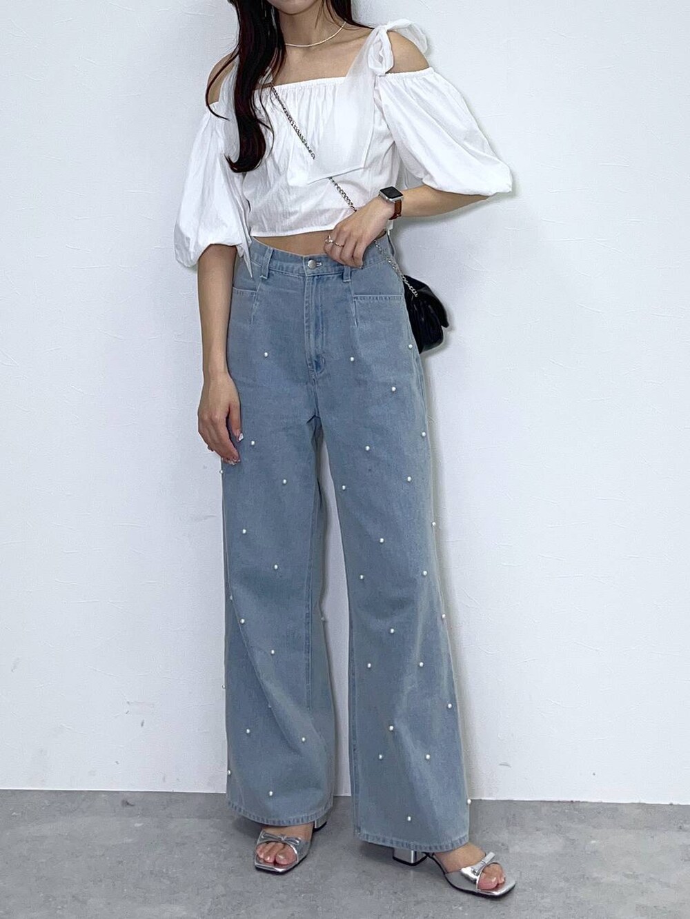 ブラック系のショルダーバッグ、ホワイト系のキャミソール、ブルー系のデニムパンツを着用したレディースの春コーディネートの6枚目の写真