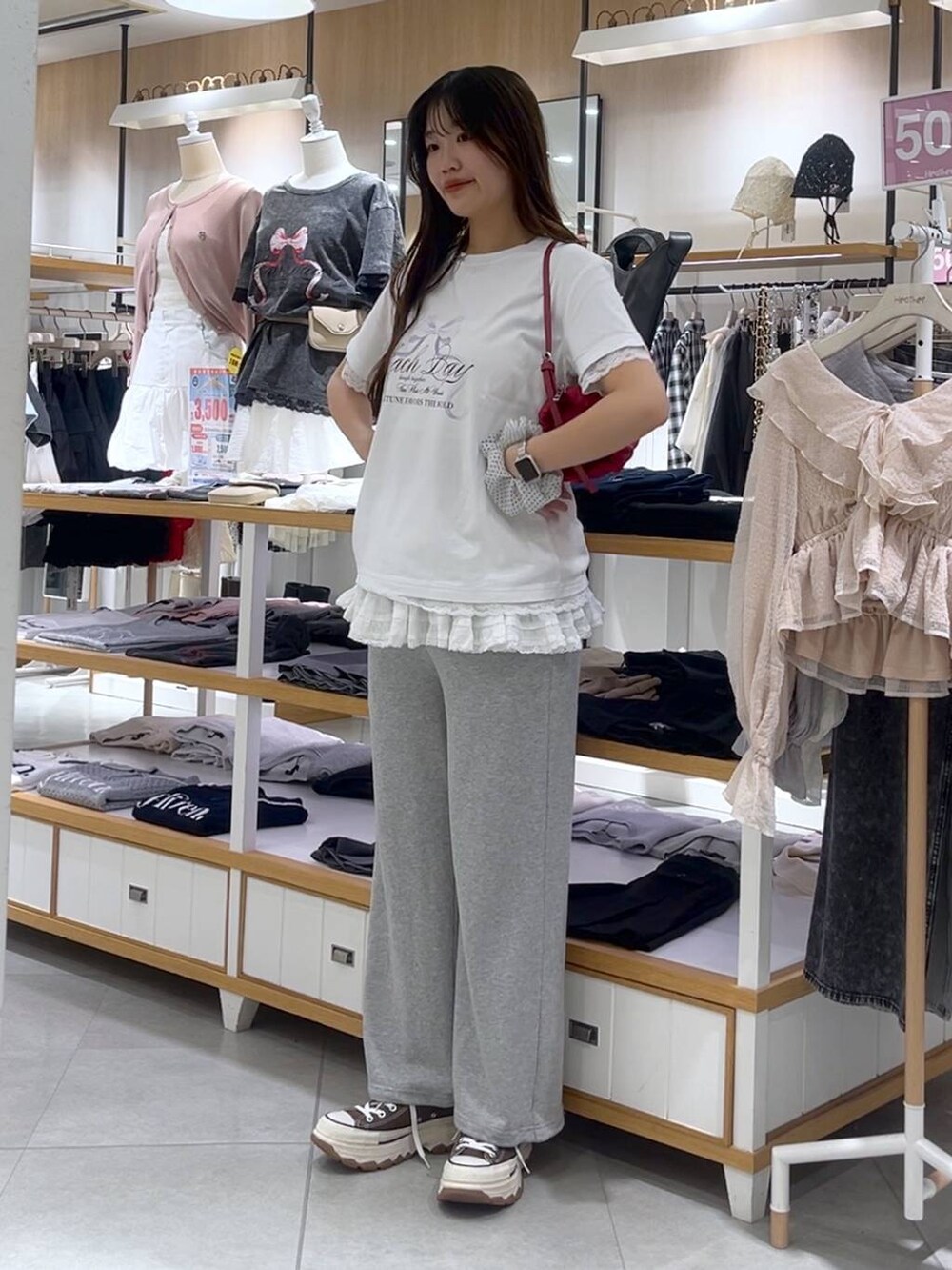 ホワイト系のキャミソール、レッド系のショルダーバッグ、グレー系のスウェットパンツを着用したレディースの春コーディネートの2枚目の写真