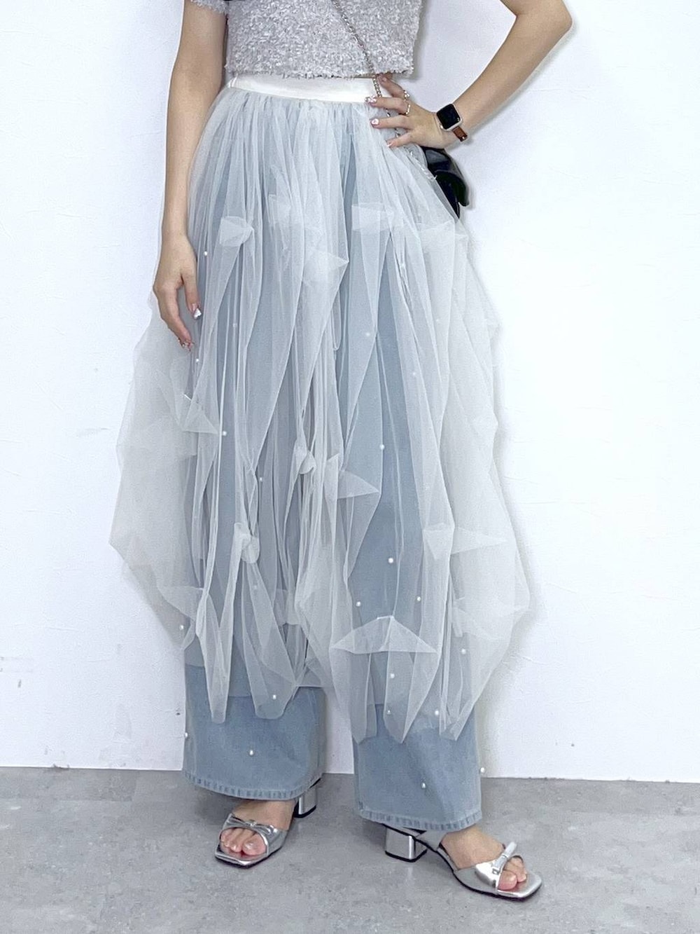 ブラック系のショルダーバッグ、ブルー系のデニムパンツ、ホワイト系のキャミソールを着用したレディースの春コーディネートの7枚目の写真